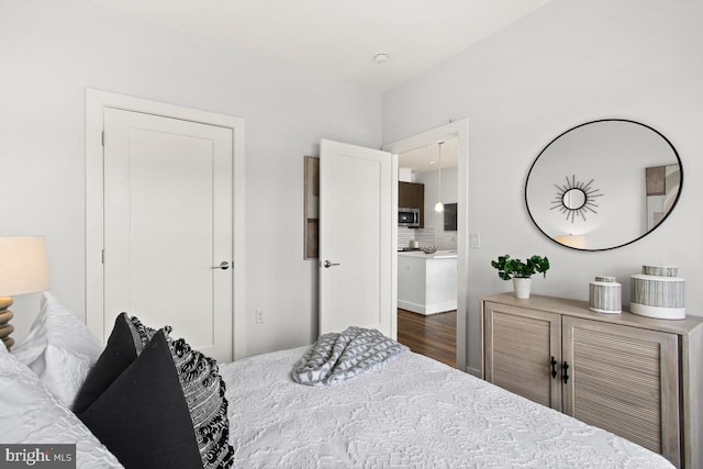 bedroom featuring connected bathroom and dark wood-type flooring