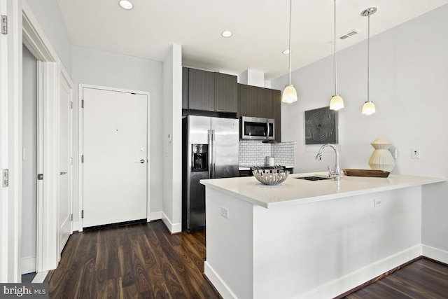 kitchen with appliances with stainless steel finishes, sink, tasteful backsplash, and dark hardwood / wood-style flooring