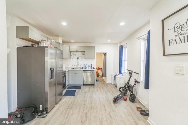 kitchen featuring gray cabinetry, stainless steel appliances, sink, light hardwood / wood-style floors, and tasteful backsplash