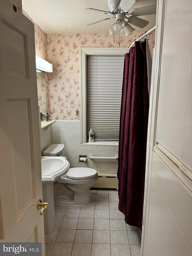 bathroom with a baseboard heating unit, sink, tile walls, tile patterned flooring, and toilet