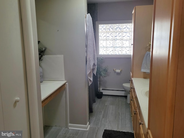 bathroom featuring a baseboard radiator, toilet, and vanity