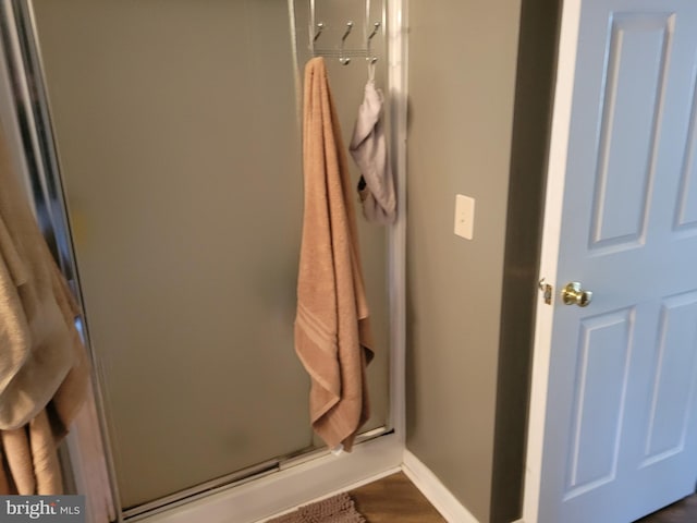 interior space with a shower with shower door and hardwood / wood-style flooring