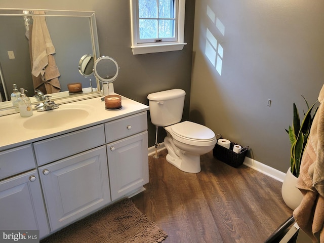 bathroom with vanity with extensive cabinet space, toilet, and hardwood / wood-style flooring