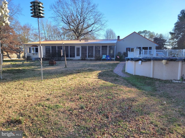 rear view of house featuring a sunroom, a covered pool, and a lawn