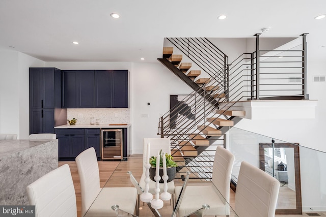 dining room featuring indoor bar, wine cooler, and light hardwood / wood-style floors