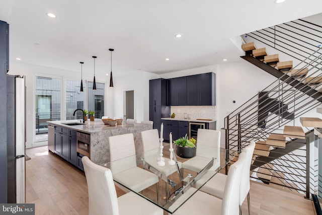 dining space featuring light hardwood / wood-style flooring, sink, and beverage cooler