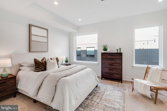 bedroom with light hardwood / wood-style floors and multiple windows