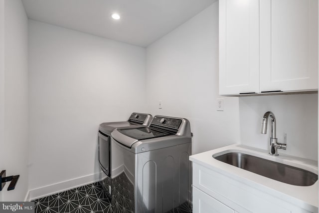 clothes washing area with sink, cabinets, dark tile floors, and separate washer and dryer