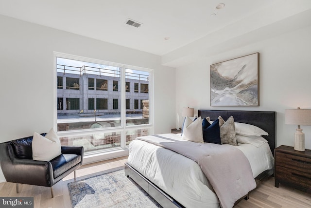 bedroom with multiple windows and light hardwood / wood-style flooring