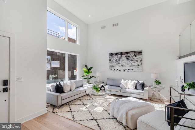 living room with light wood-type flooring and a high ceiling