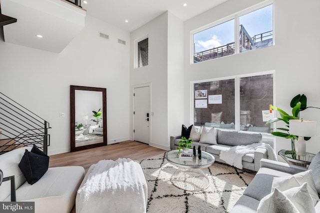 living room with a towering ceiling and light wood-type flooring