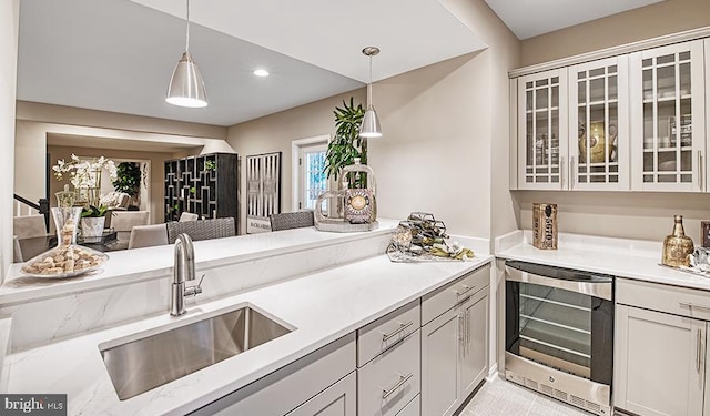 kitchen featuring glass insert cabinets, wine cooler, decorative light fixtures, and a sink