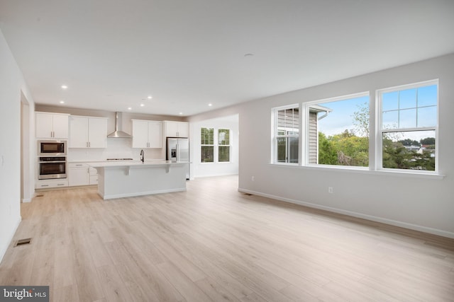 unfurnished living room featuring light wood-style floors, visible vents, baseboards, and recessed lighting