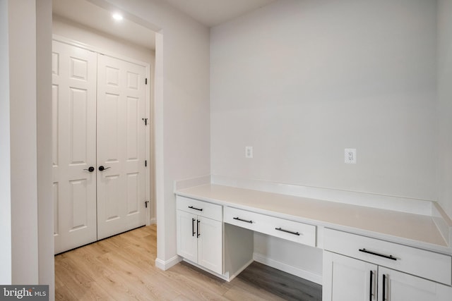 unfurnished office with light wood-type flooring and built in desk