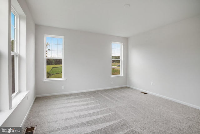 carpeted spare room with visible vents and baseboards