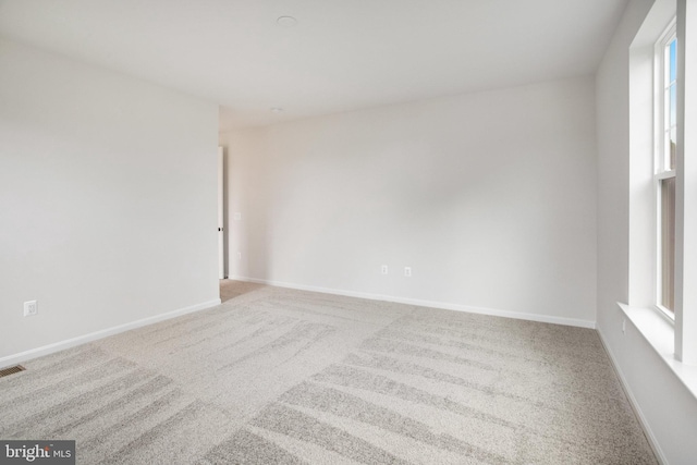 carpeted empty room with visible vents and baseboards