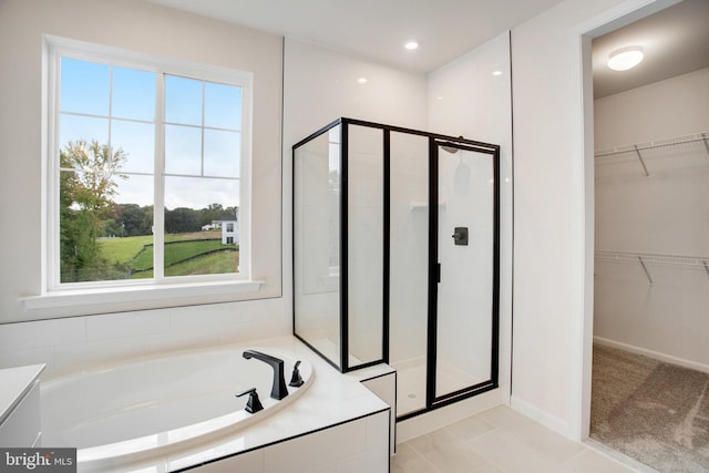 full bathroom featuring a stall shower, a spacious closet, and a bath