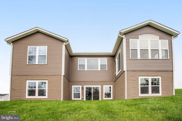 rear view of property with brick siding and a yard