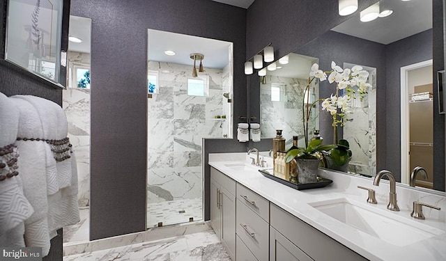 bathroom featuring a tile shower, marble finish floor, double vanity, and a sink