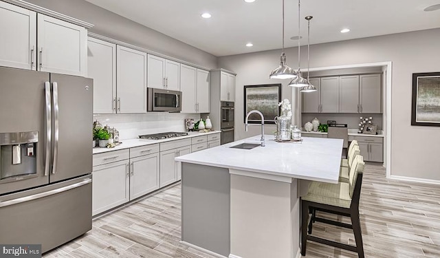 kitchen featuring stainless steel appliances, a sink, light wood-style floors, light countertops, and tasteful backsplash