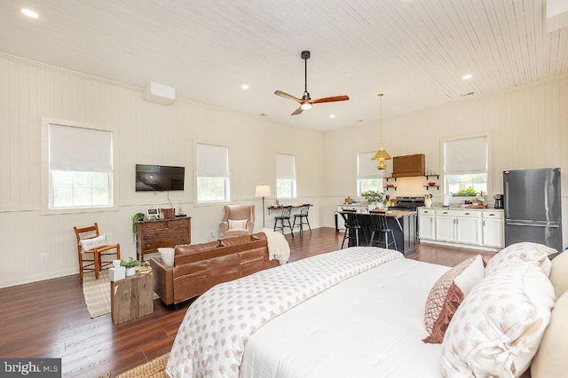 bedroom with dark hardwood / wood-style floors, stainless steel fridge, and multiple windows