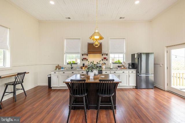 kitchen with dark hardwood / wood-style flooring, stainless steel refrigerator, white cabinetry, a healthy amount of sunlight, and pendant lighting