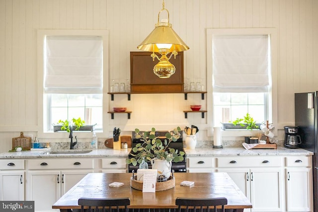 kitchen featuring light stone countertops, white cabinetry, and a wealth of natural light