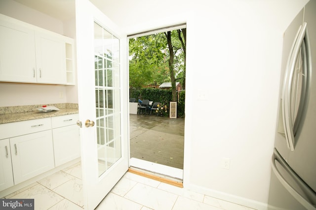 kitchen featuring white cabinetry, light stone countertops, and stainless steel refrigerator