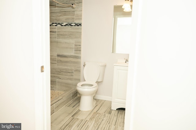 bathroom with vanity, toilet, and a tile shower