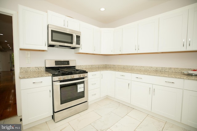 kitchen with light stone countertops, stainless steel appliances, and white cabinets