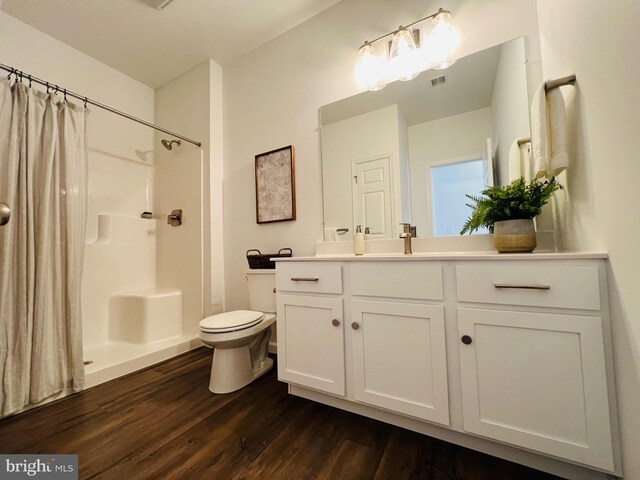 bathroom with hardwood / wood-style floors, vanity, curtained shower, and toilet