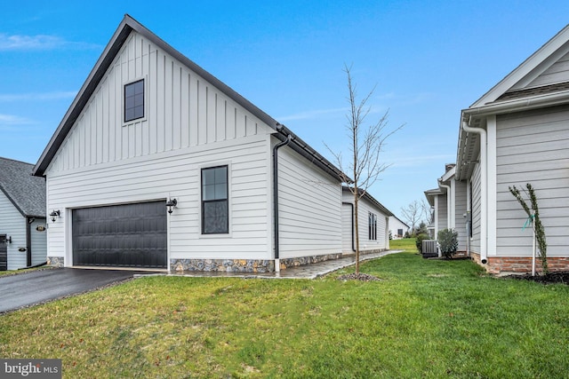 view of side of property featuring a garage, central AC unit, and a lawn