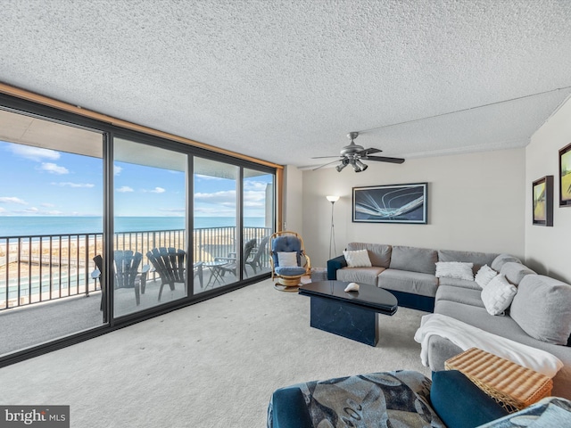 living room with carpet, ceiling fan, a healthy amount of sunlight, and a water view