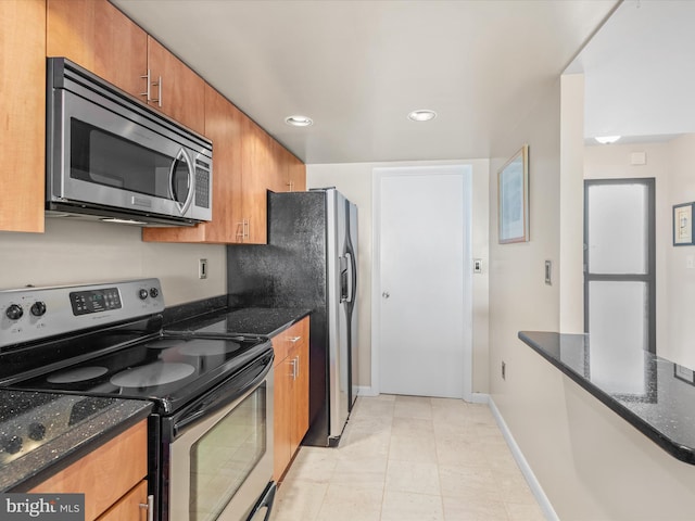 kitchen with dark stone counters, stainless steel appliances, and light tile floors