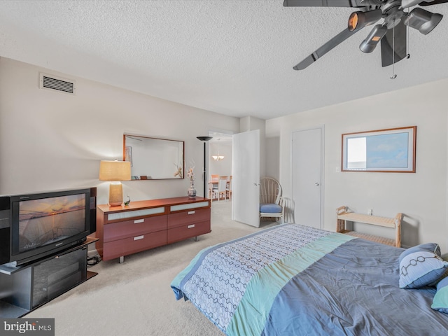 carpeted bedroom featuring ceiling fan and a textured ceiling