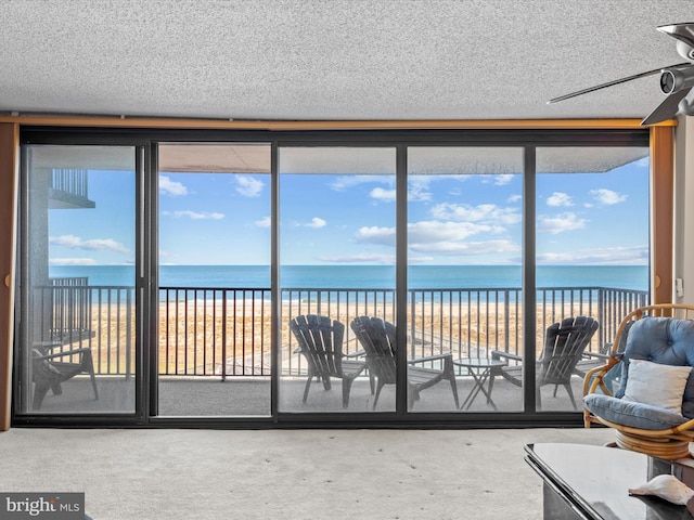 unfurnished sunroom featuring plenty of natural light, a beach view, a water view, and ceiling fan