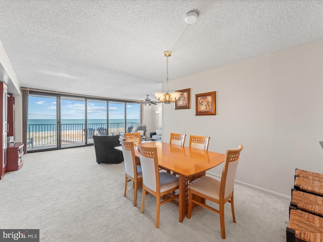 dining room featuring a water view, a wall of windows, a notable chandelier, a textured ceiling, and light colored carpet