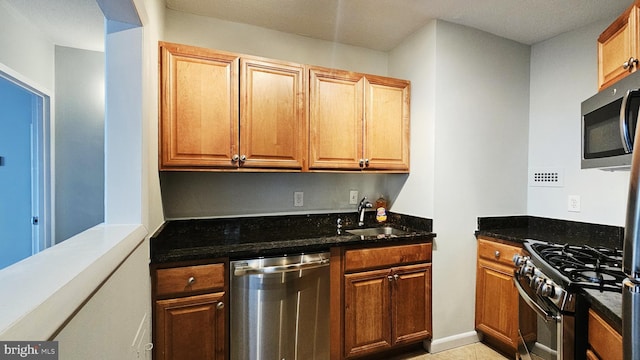 kitchen with sink, stainless steel appliances, and dark stone countertops