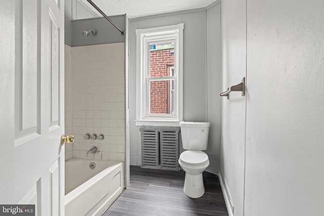 bathroom with a textured ceiling, wood finished floors, toilet, and shower / bathtub combination