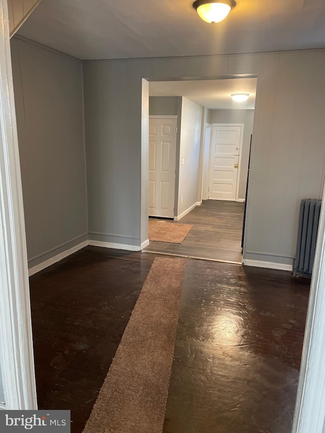 unfurnished room featuring dark hardwood / wood-style flooring and radiator heating unit