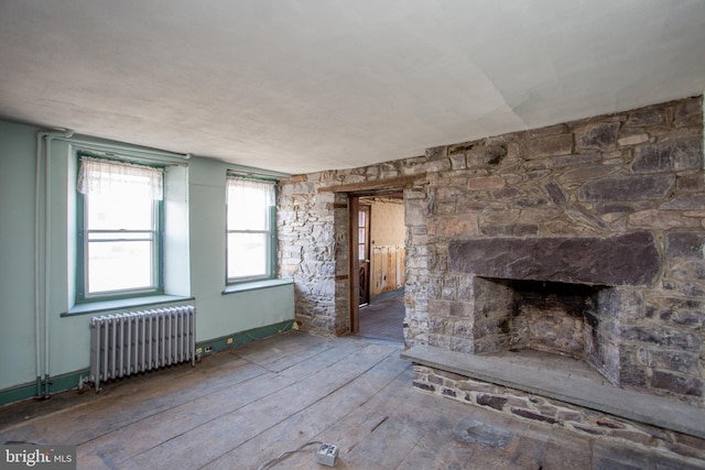 interior space with dark hardwood / wood-style flooring, a stone fireplace, and radiator