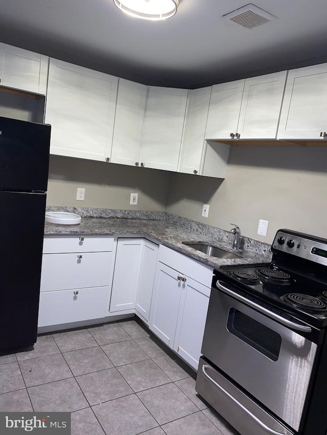 kitchen featuring black fridge, white cabinets, stainless steel range with electric cooktop, sink, and light tile flooring