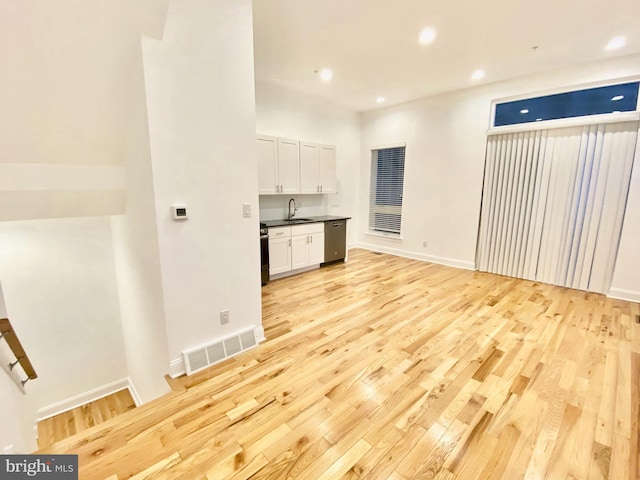 kitchen featuring range, light hardwood / wood-style floors, white cabinetry, dishwasher, and sink