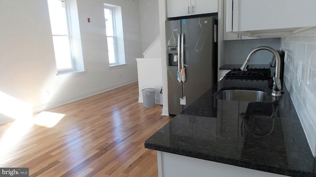 kitchen with dark stone counters, plenty of natural light, stainless steel fridge with ice dispenser, and light wood-type flooring