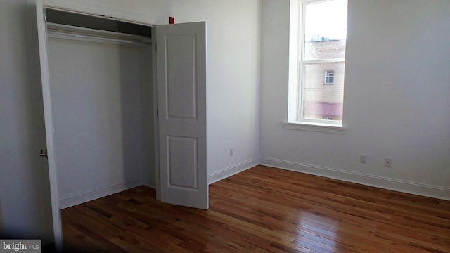 unfurnished bedroom with a closet and dark hardwood / wood-style flooring