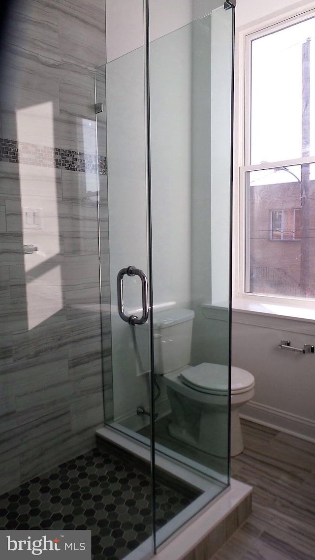 bathroom featuring plenty of natural light, tile flooring, a shower with shower door, and toilet