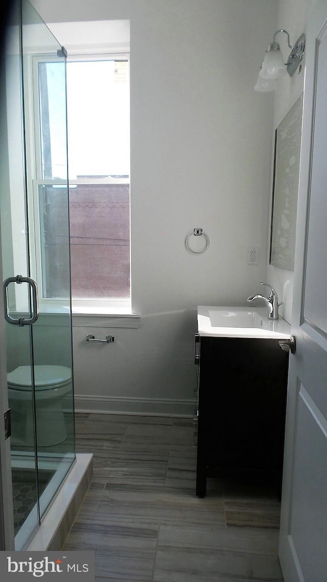 bathroom with tile floors, walk in shower, toilet, and vanity