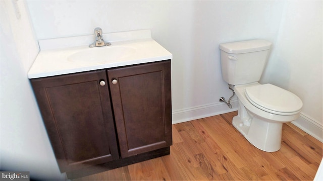 bathroom with toilet, hardwood / wood-style floors, and vanity