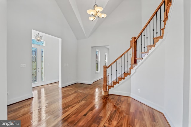 entryway featuring french doors, high vaulted ceiling, wood-type flooring, and an inviting chandelier