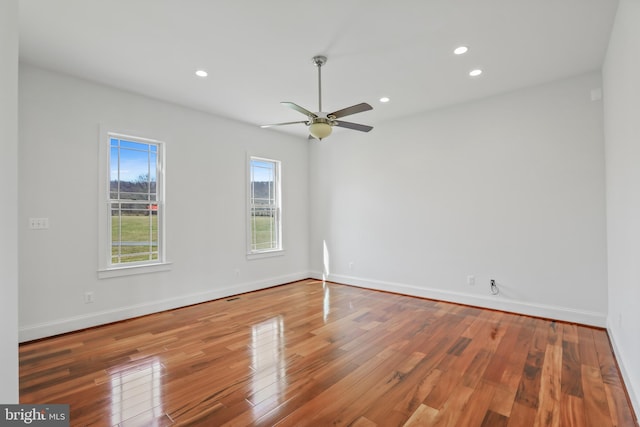 unfurnished room featuring a healthy amount of sunlight, hardwood / wood-style floors, and ceiling fan